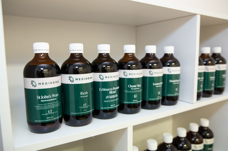 A row of bottles with green labels are lined up on a shelf.