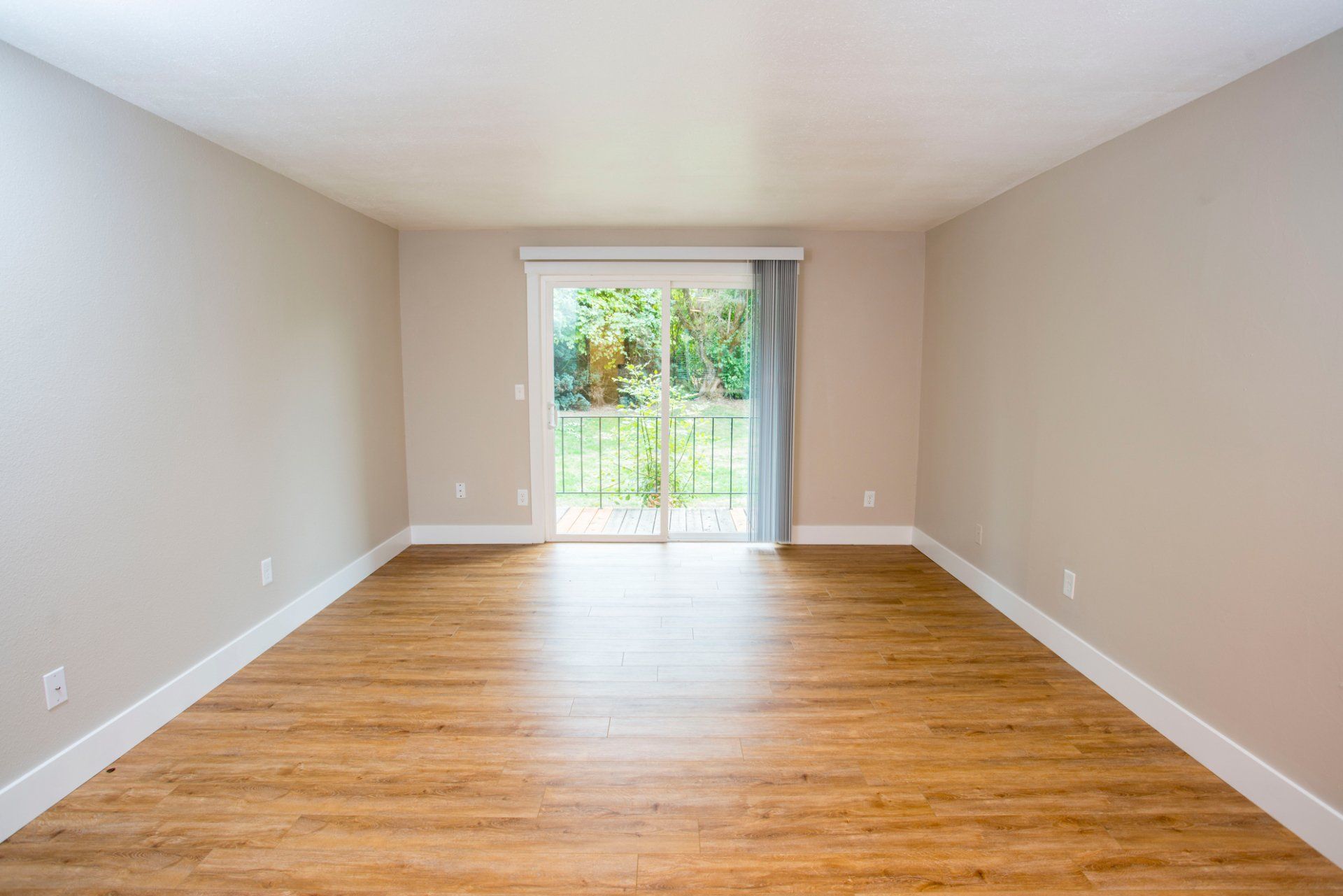 Interior of empty living room with wood flooring and a glass sliding door
