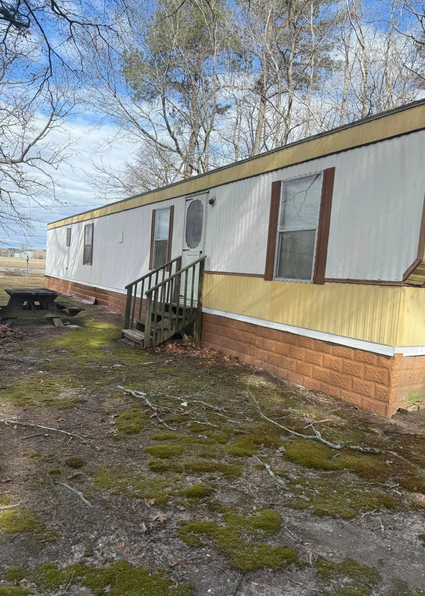 A mobile home with stairs and a picnic table in front of it.