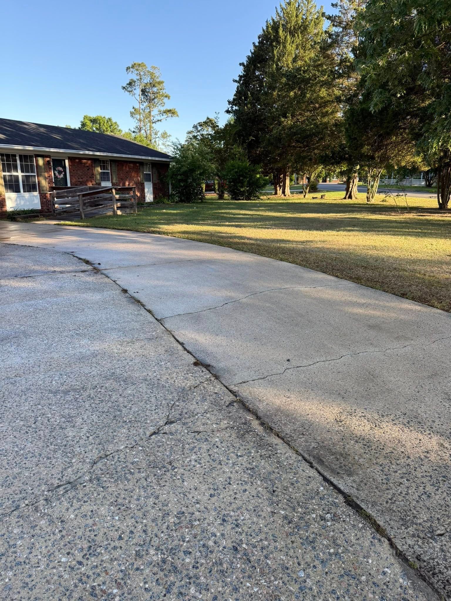 A driveway leading to a house with trees in the background.
