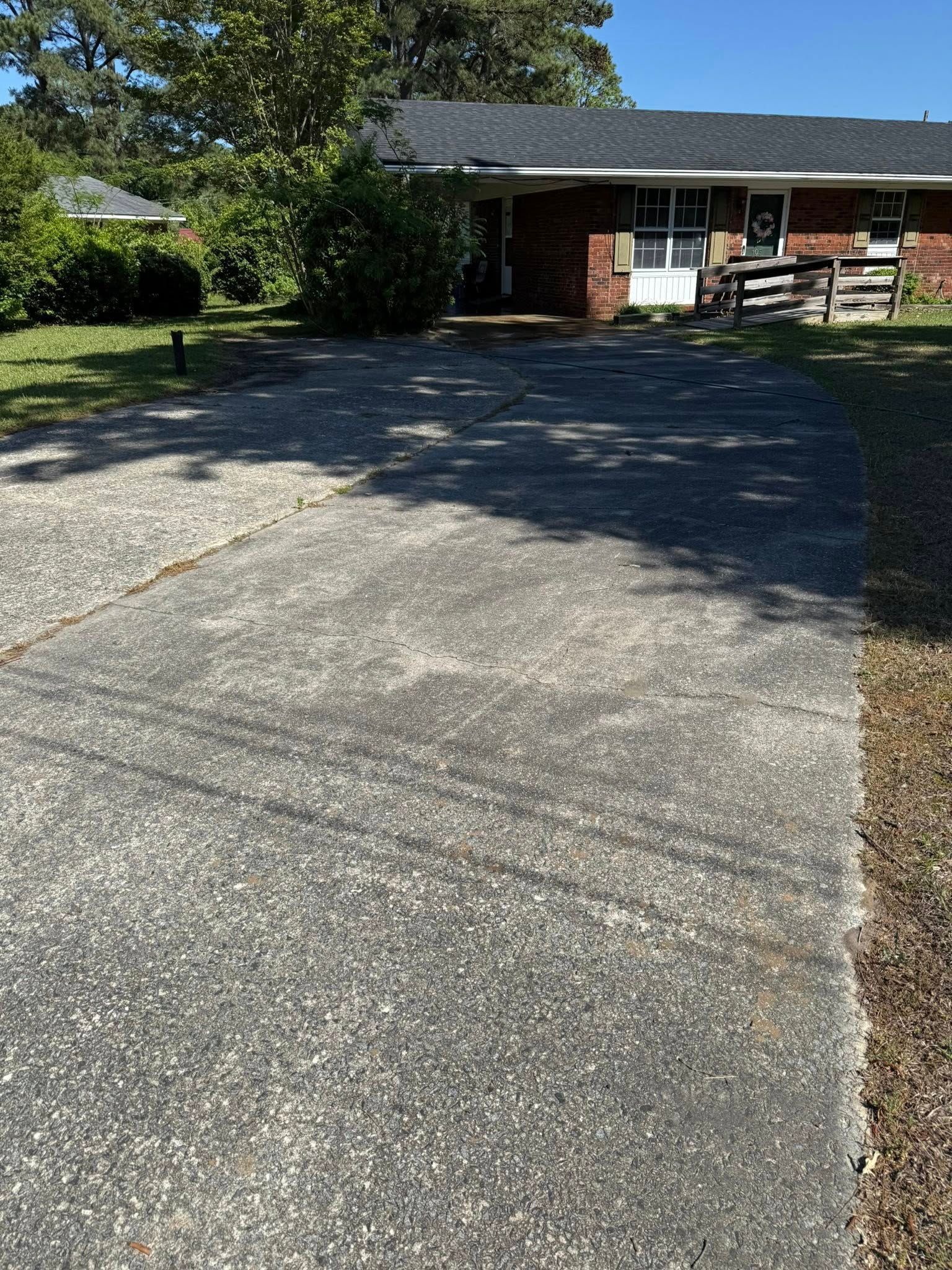 A driveway leading to a brick house on a sunny day.