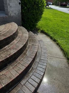A set of brick steps leading up to a brick building next to a sidewalk.