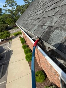 A person is cleaning a gutter on the side of a building.