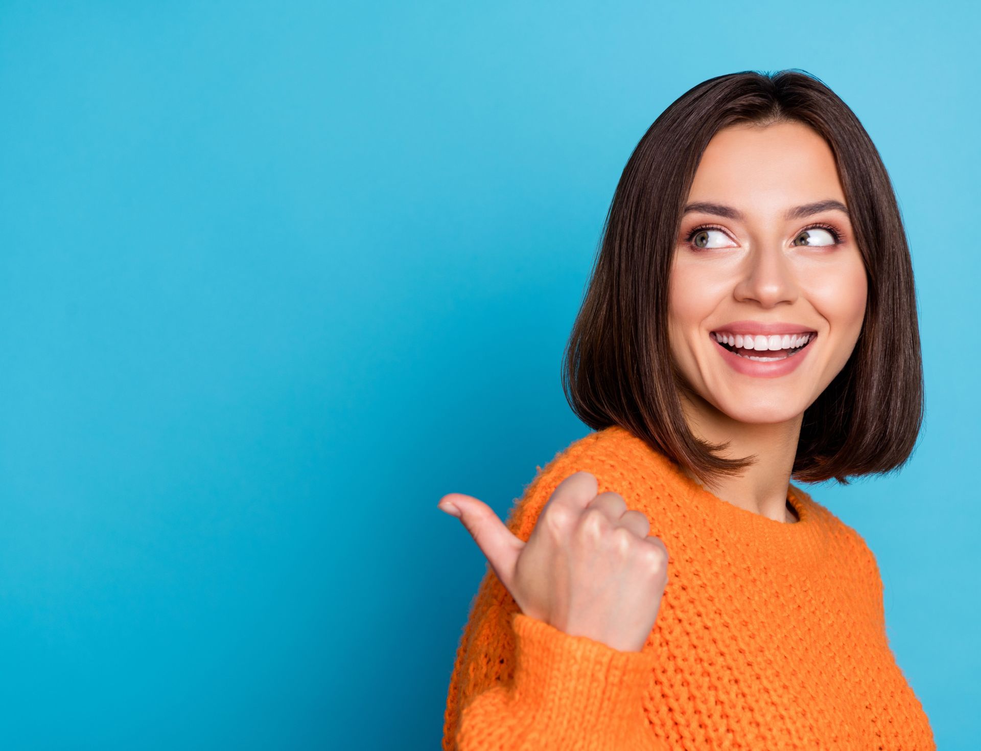 a woman in an orange sweater is giving a thumbs up