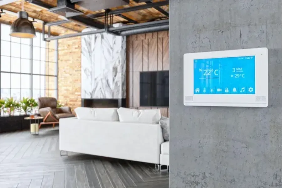 Modern living room with a white sofa and a wall-mounted touchscreen thermostat on a concrete wall
