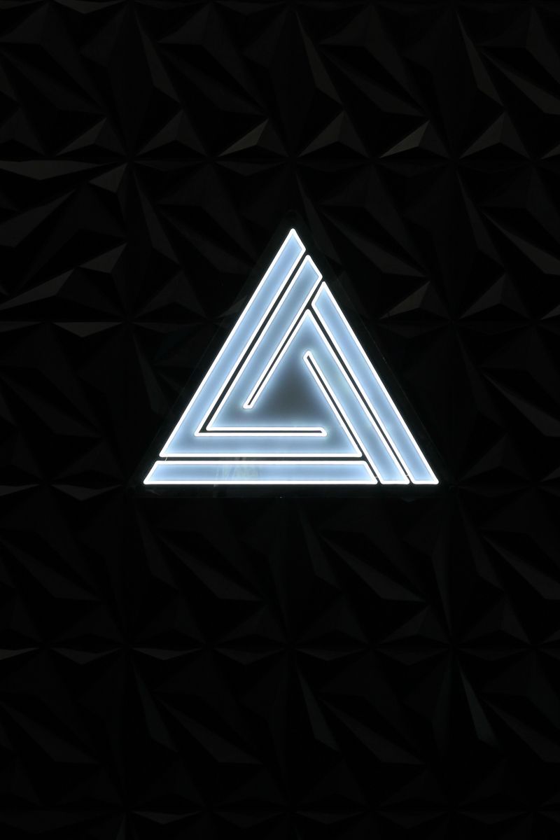 Glowing blue triangle on black textured background.