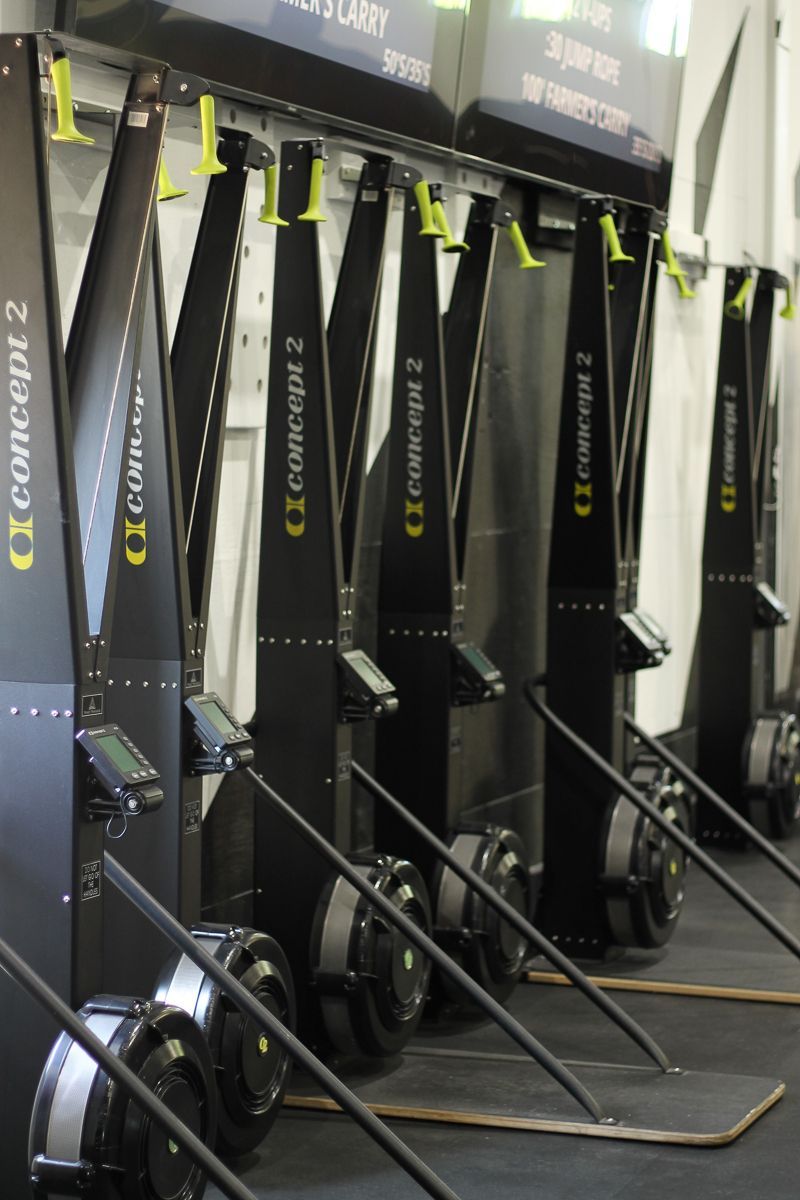 Rowing machines lined up in a gym, black and gray with digital displays.