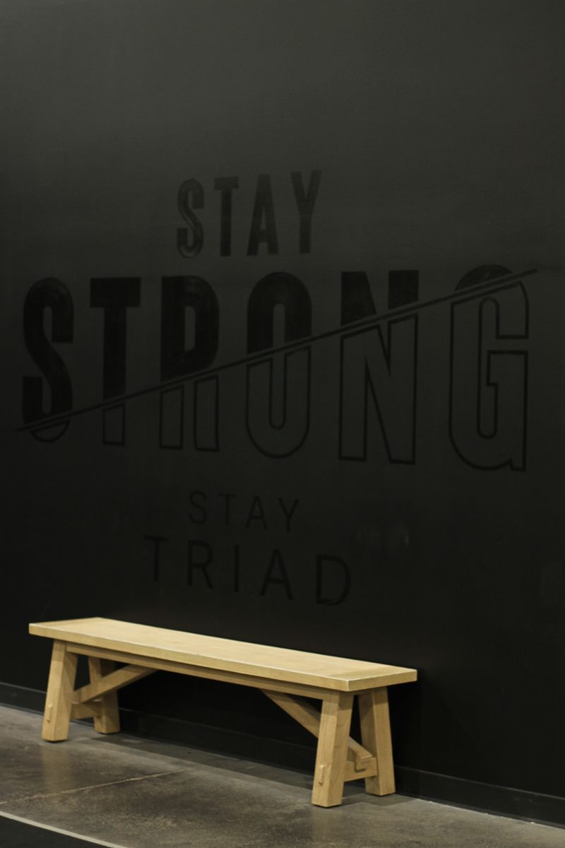 Wooden bench in front of a black wall with the words 