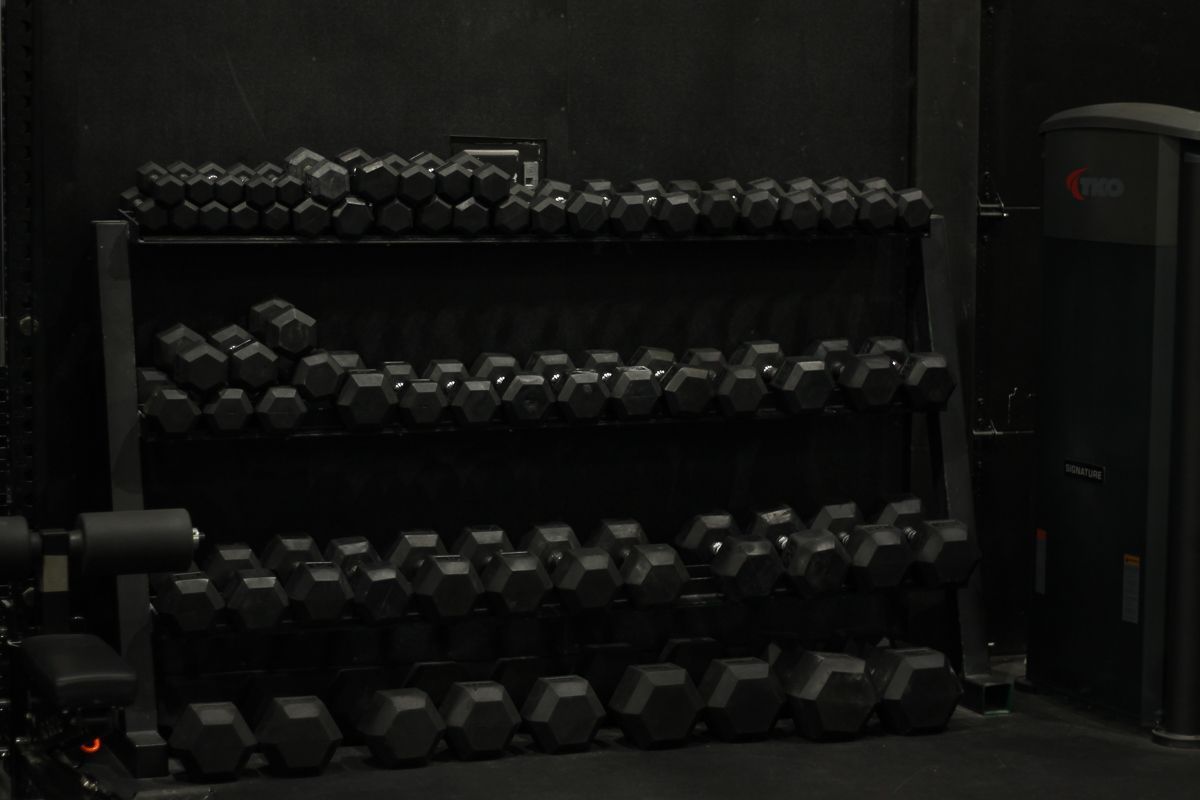 Black dumbbells on a black rack in a gym setting.