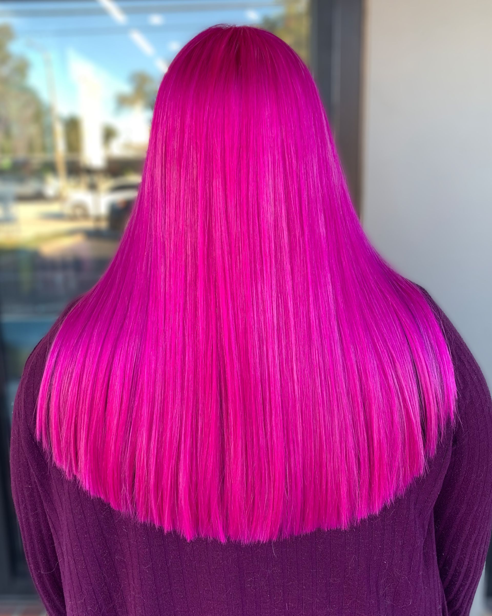Back view of long, vibrant magenta hair with a crimped texture, worn by a person in a purple sweater.