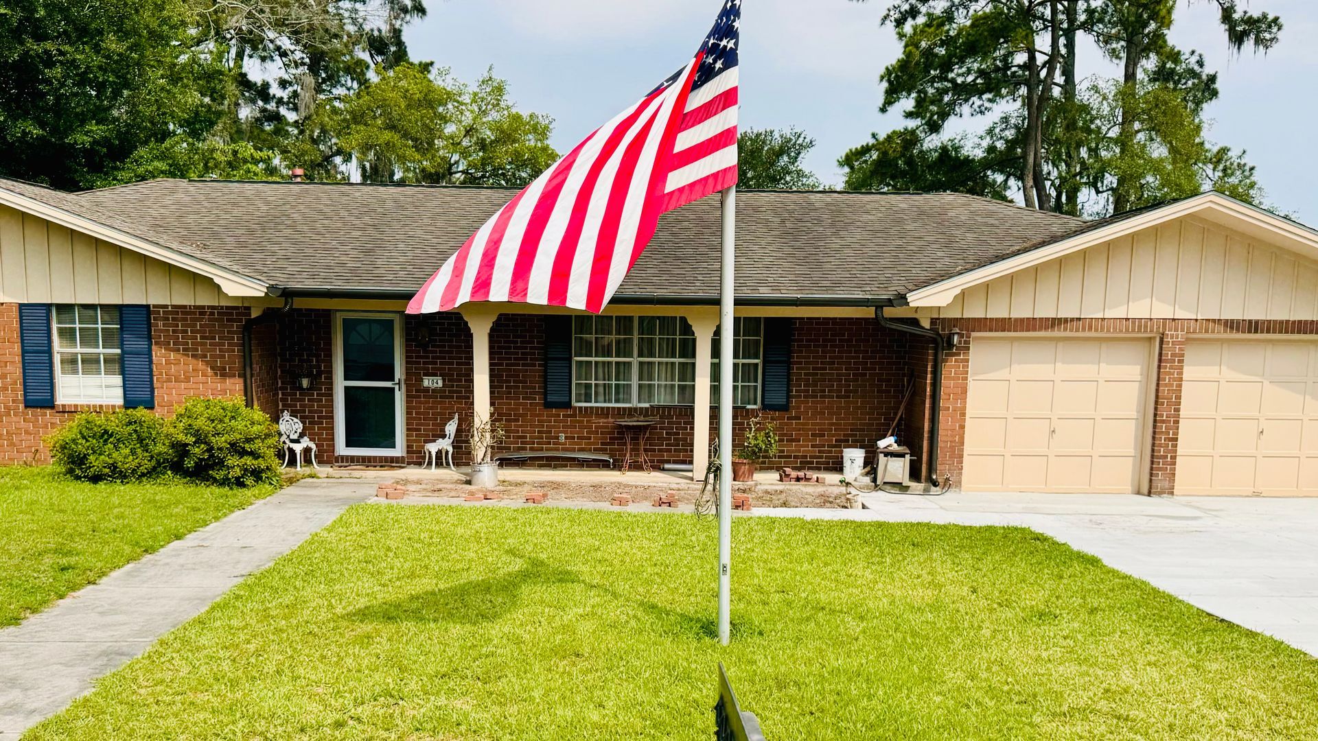 An american flag is flying in front of a brick house.