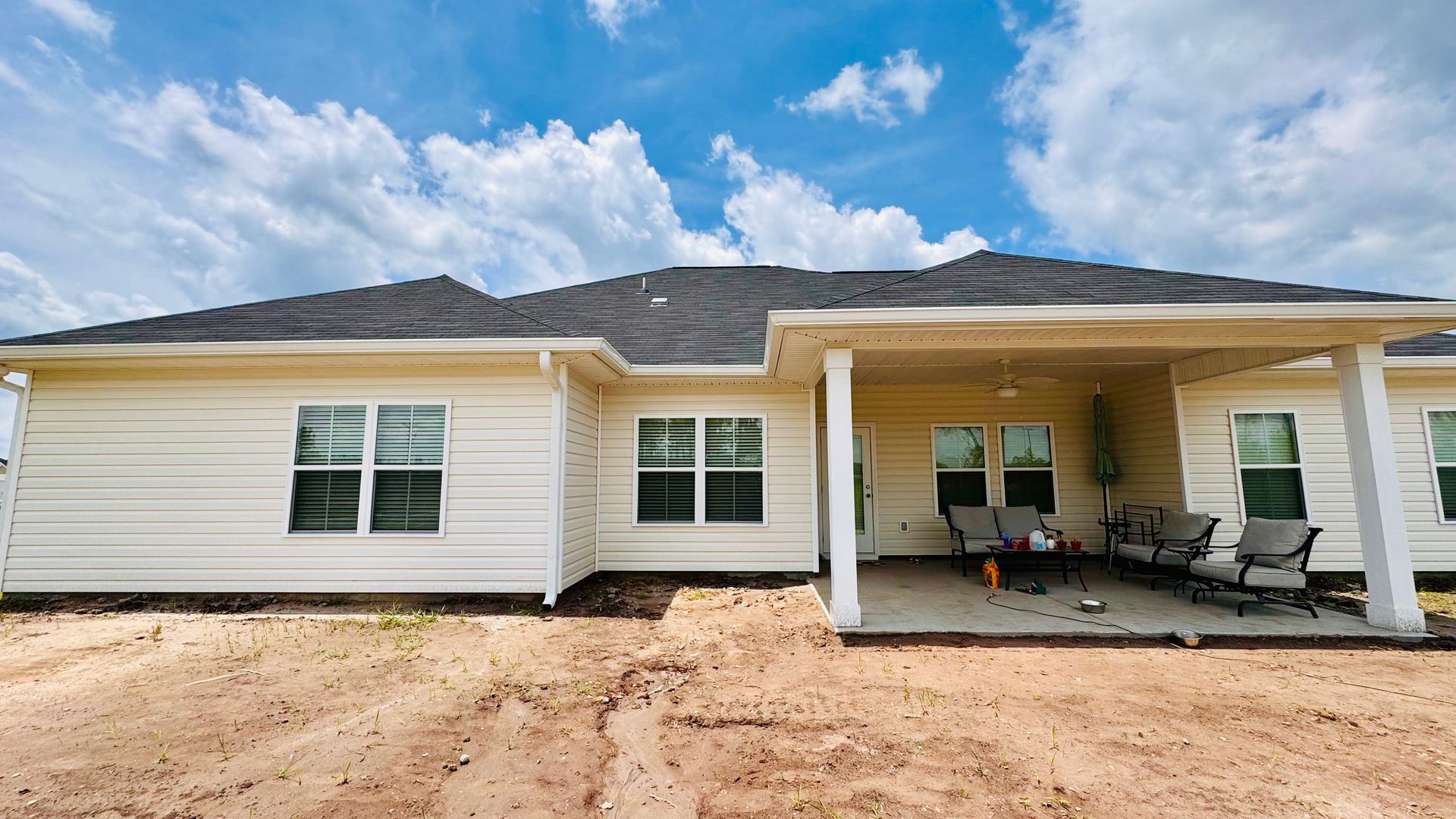 A white house with a porch and chairs in front of it.
