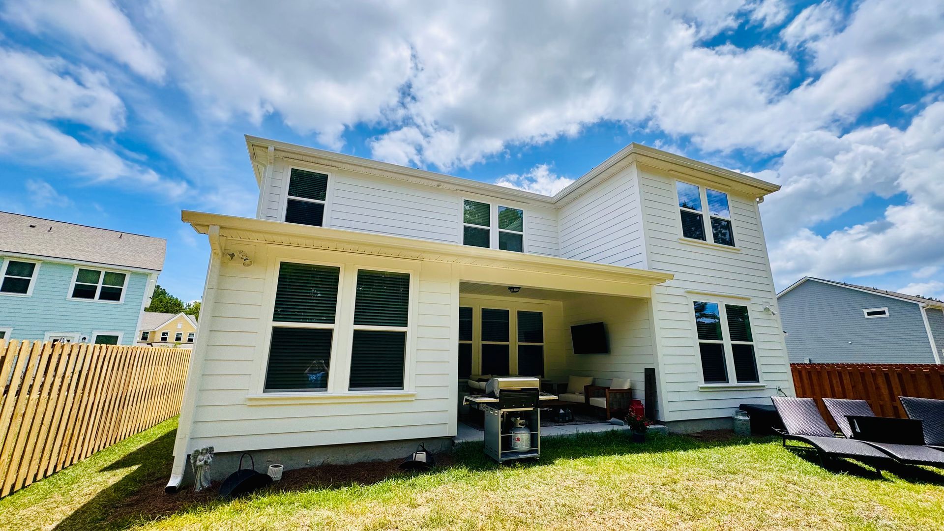 A large white house with a lot of windows is sitting on top of a lush green lawn.
