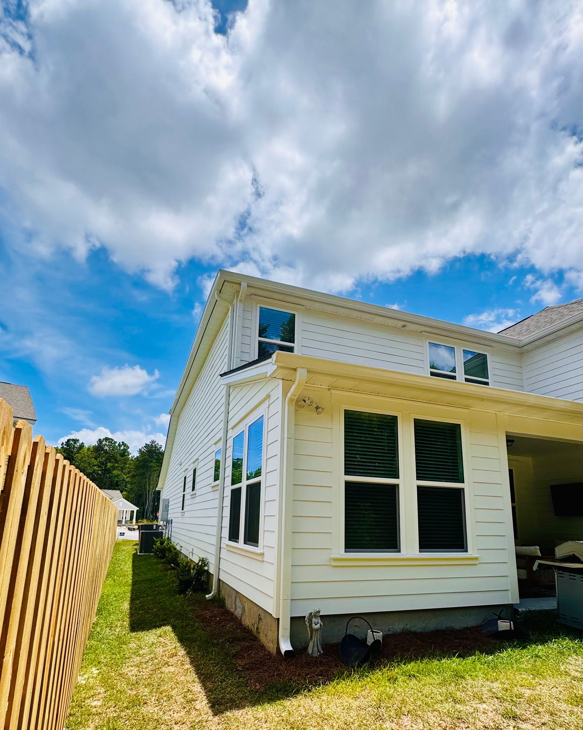 A white house with a wooden fence in front of it on a sunny day.