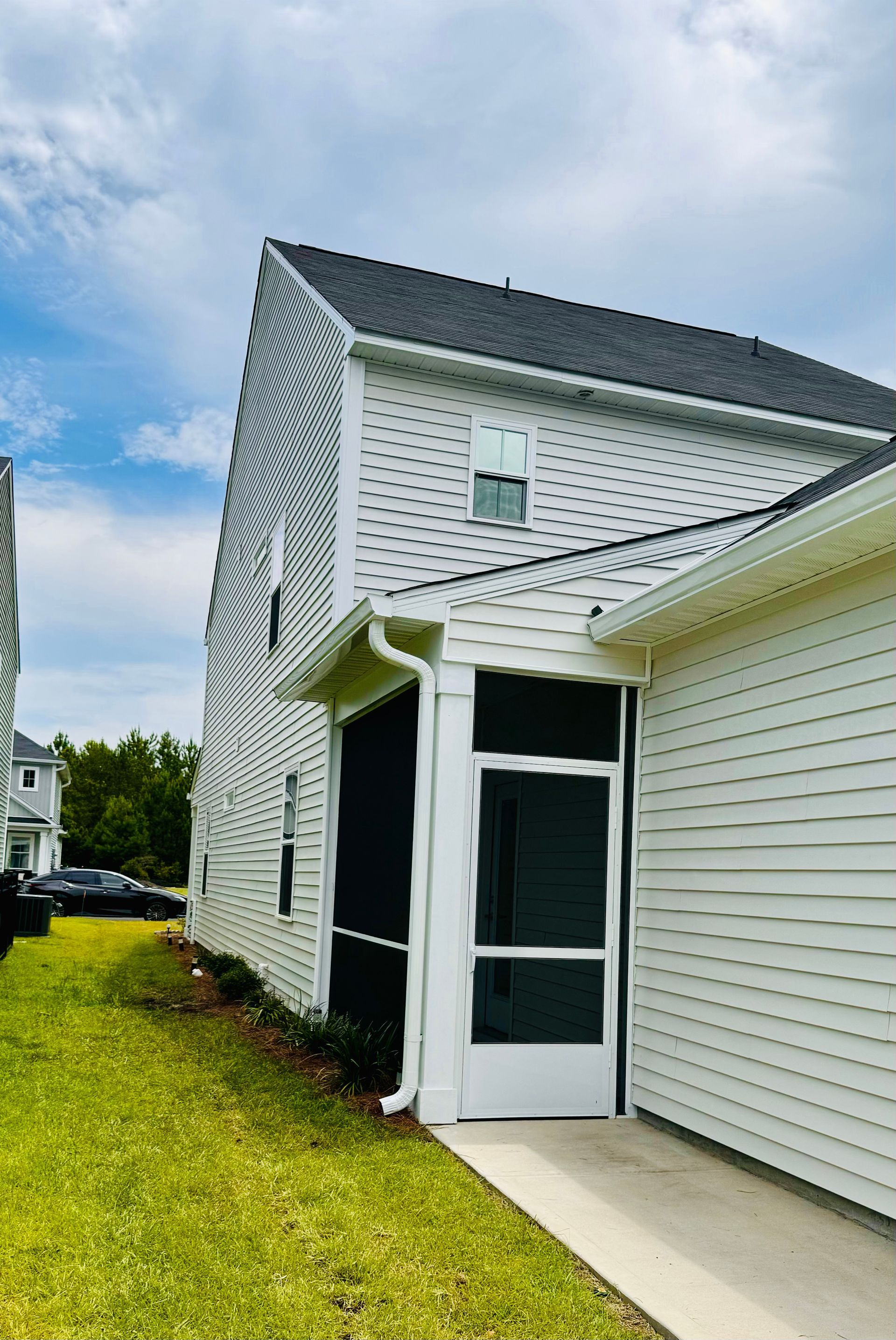 A white house with a screened in porch on the side of it.
