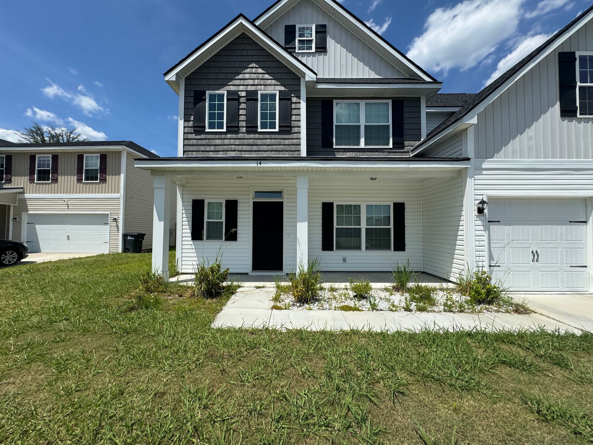 A large white house with black shutters and a car parked in front of it.