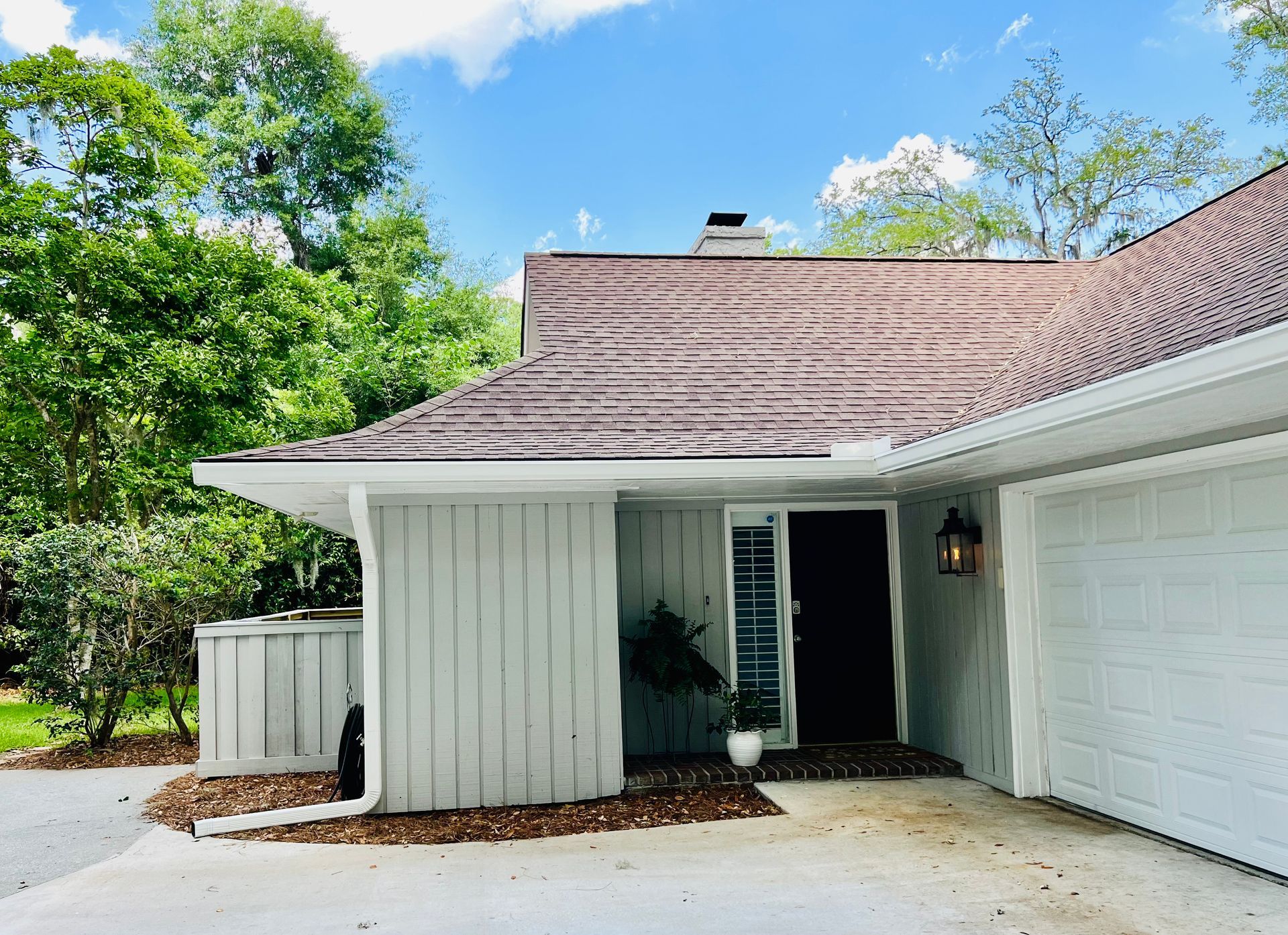 A white house with a brown roof and a garage.