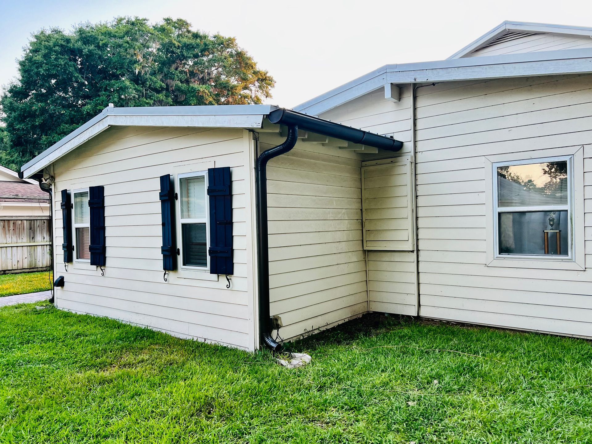 A white house with black shutters is sitting on top of a lush green lawn.