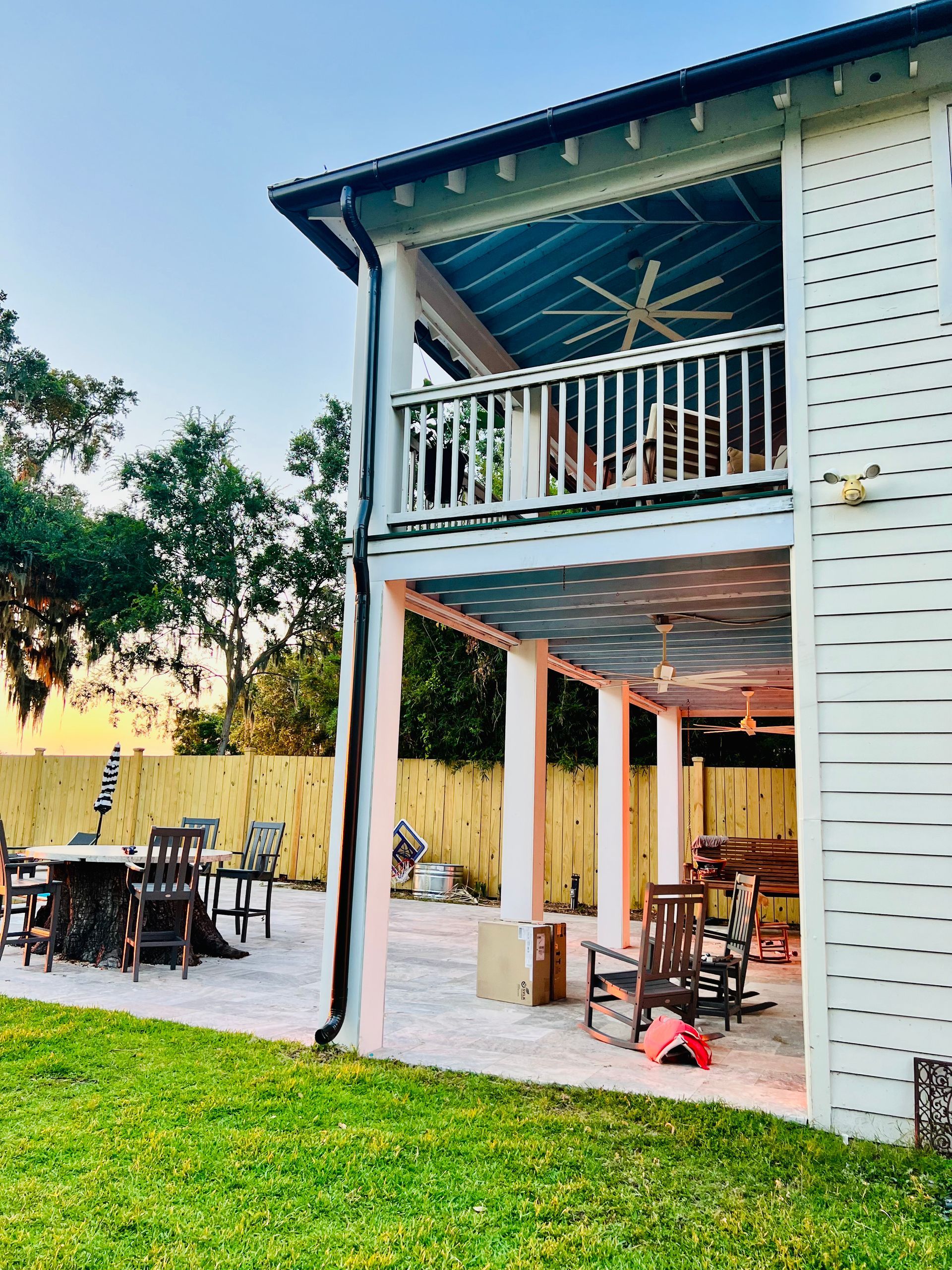 A white house with a balcony and a patio with chairs and tables.