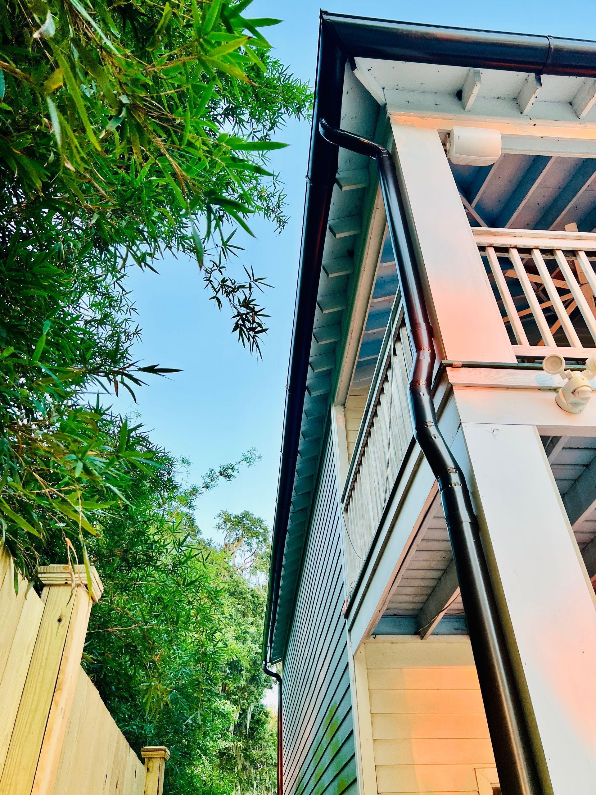 A white house with a black gutter on the side of it