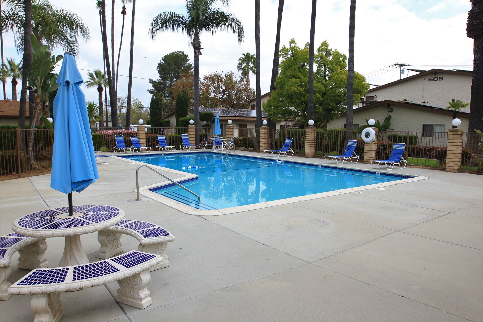 A large swimming pool with a blue umbrella and a picnic table