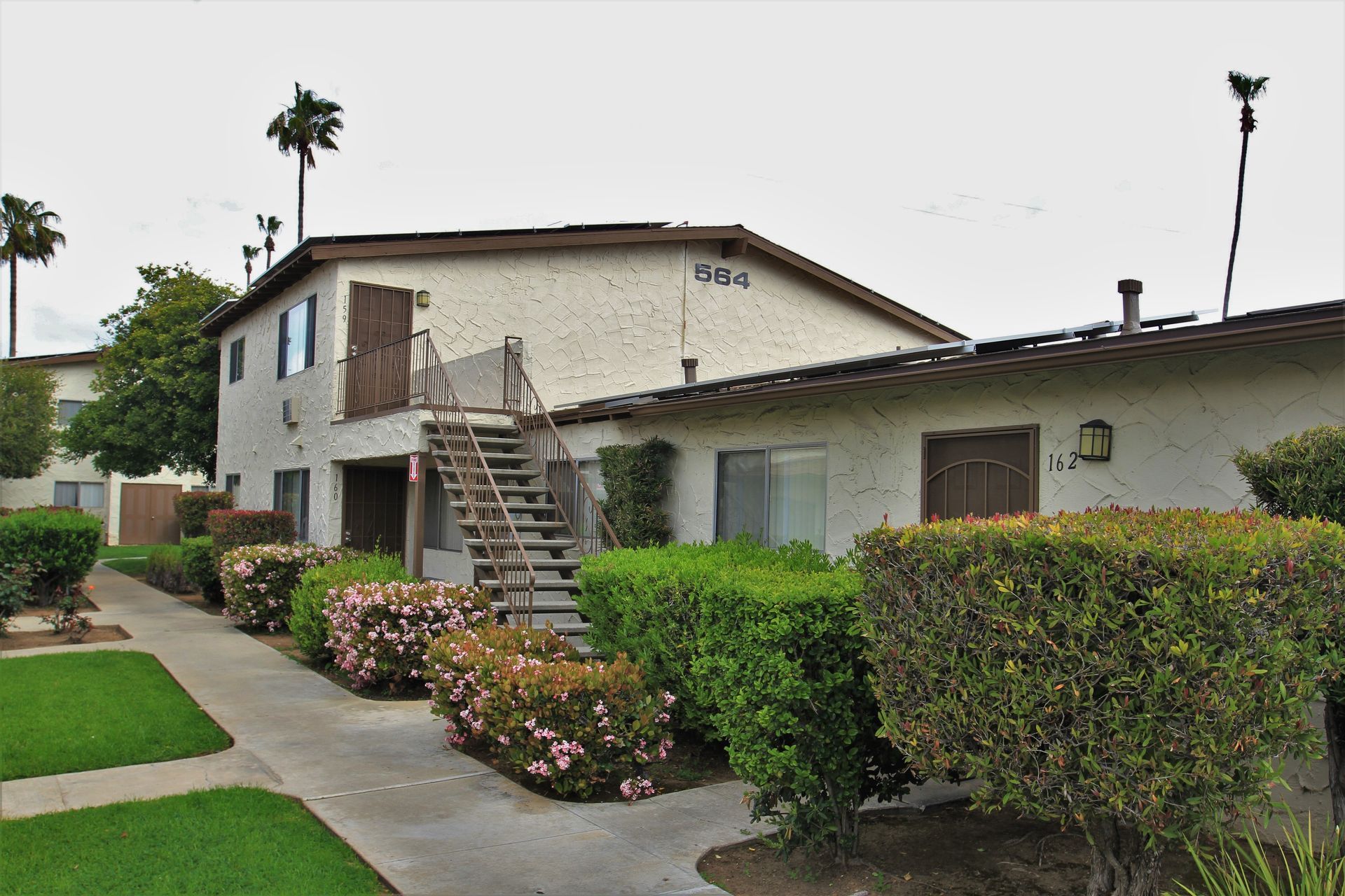A white apartment building with stairs leading up to the second floor