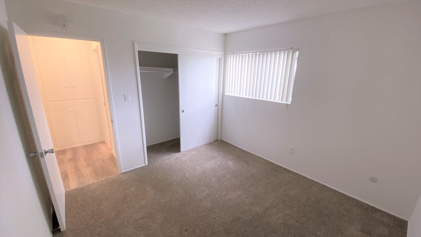 An empty bedroom with a closet and a window.