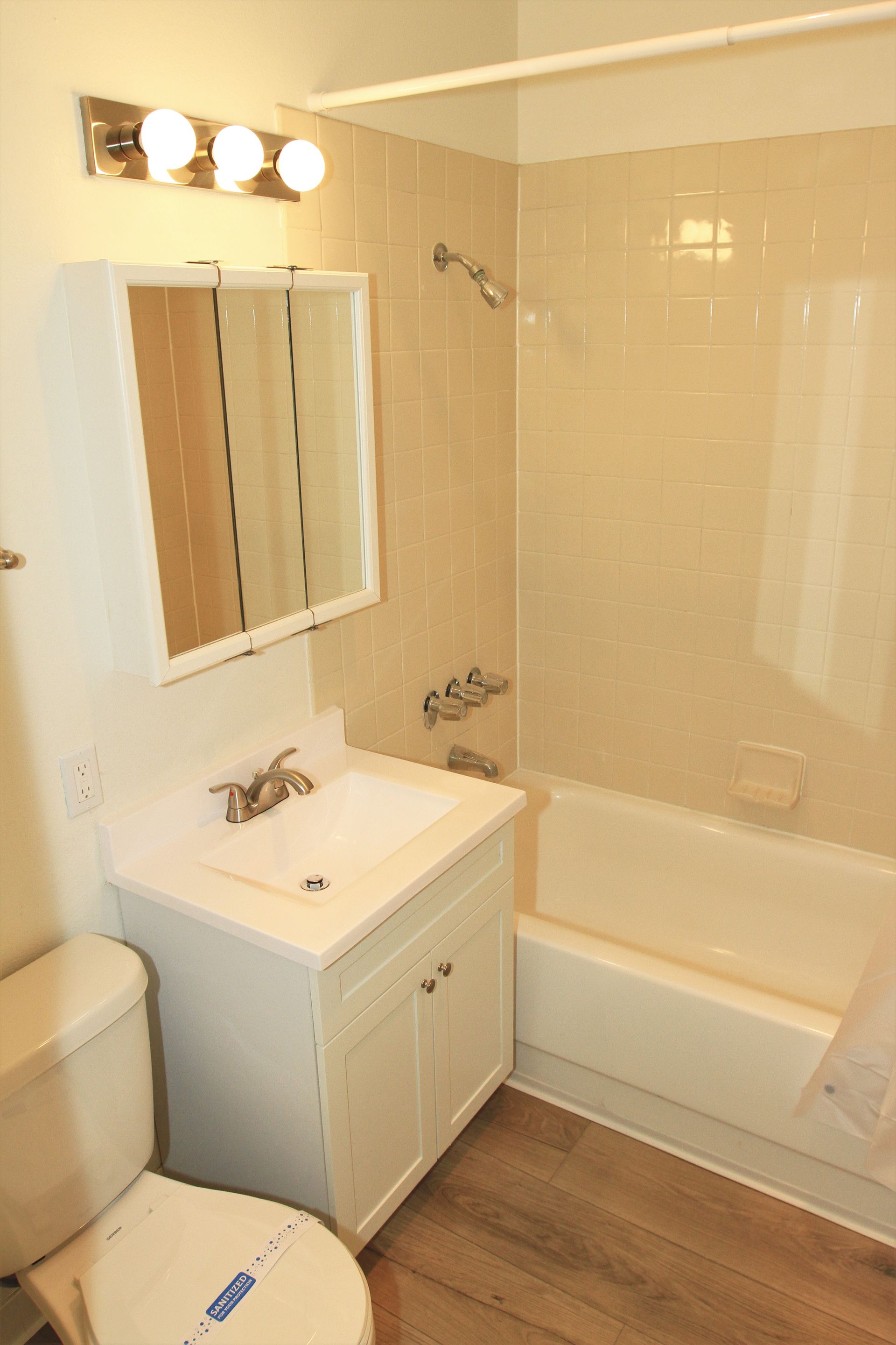 A bathroom with a toilet , sink , tub and mirror.