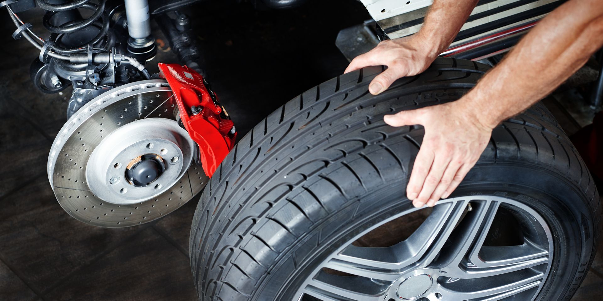 A man is changing a tire on a car in a garage. | Halton Auto Service & Transmission