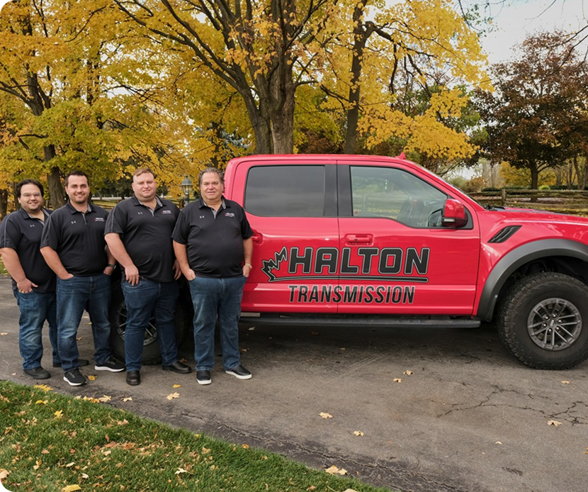 A group of men standing in front of a red truck that says halton transmission | Halton Auto Service