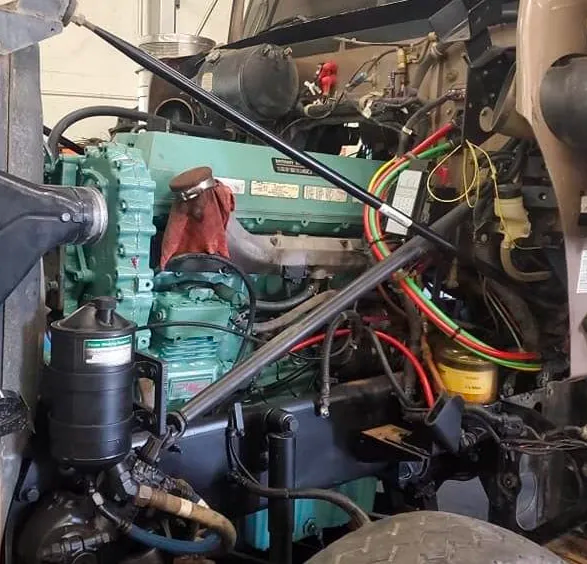 A green diesel engine is sitting under the hood of a truck