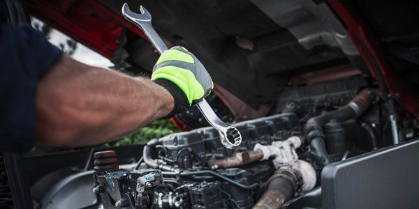 A man is working on a car engine with a wrench.