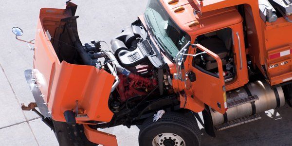 An orange truck with its hood open is parked on the side of the road.