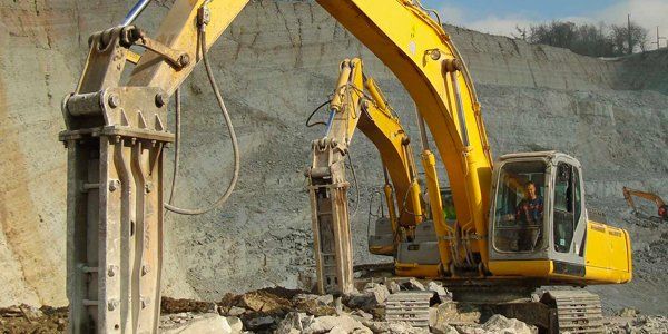Two yellow excavators are working in a quarry.