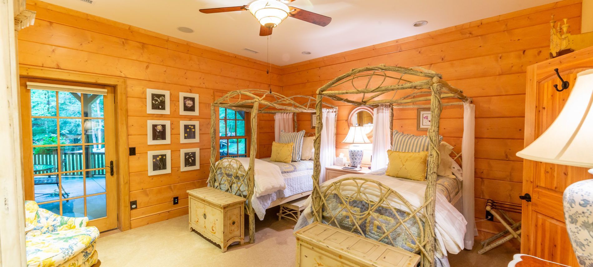 A bedroom in a log cabin with two beds and a ceiling fan.