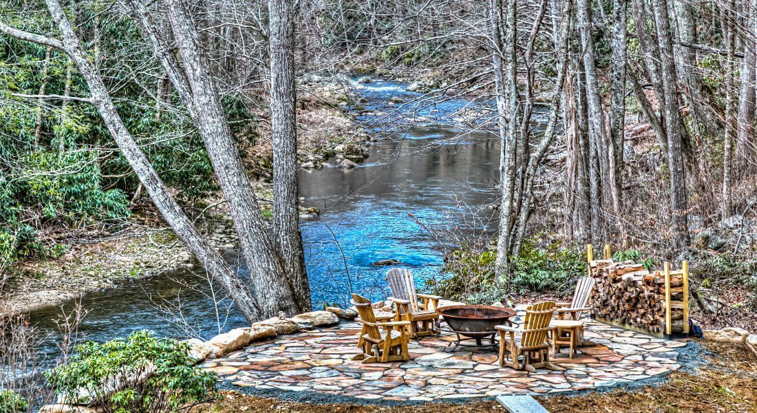 A fire pit in the middle of a forest next to a river.