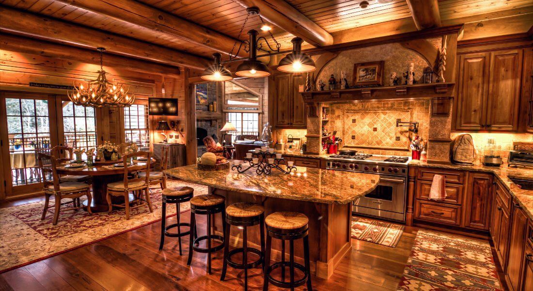 A kitchen in a log cabin with a large island and stools.