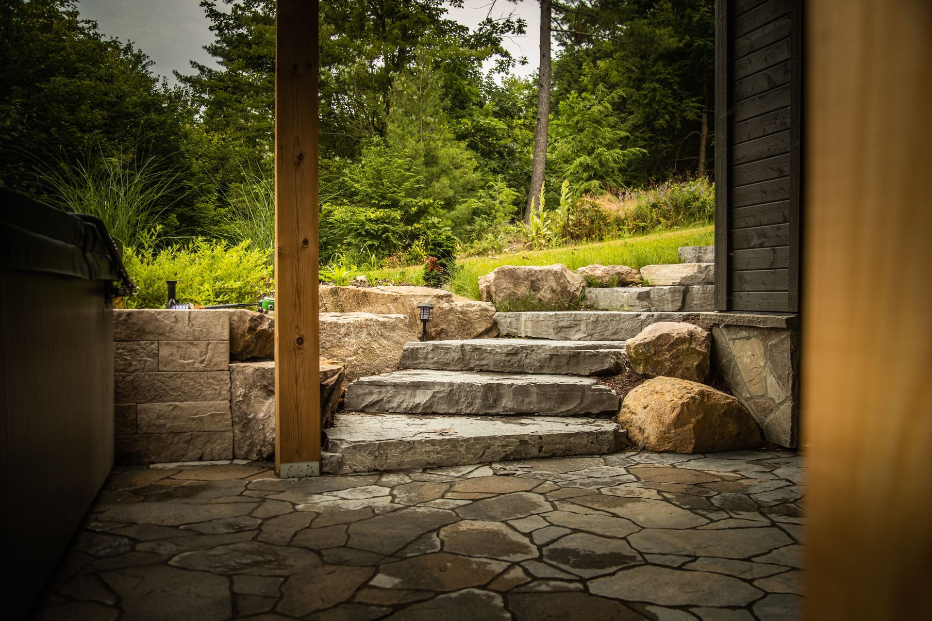 Stone steps leading up to a grassy area, accessed from a patio.