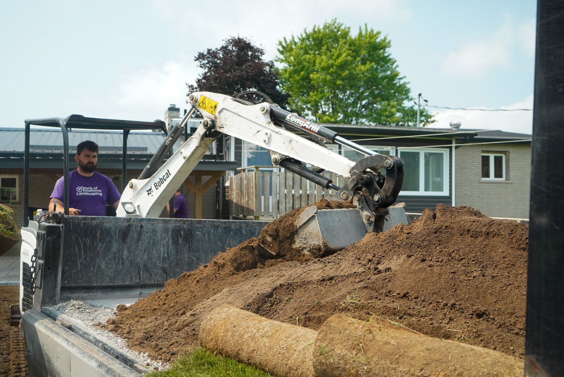 Mini excavator loading soil during landscape excavation in Kingston, preparing the site for grading.