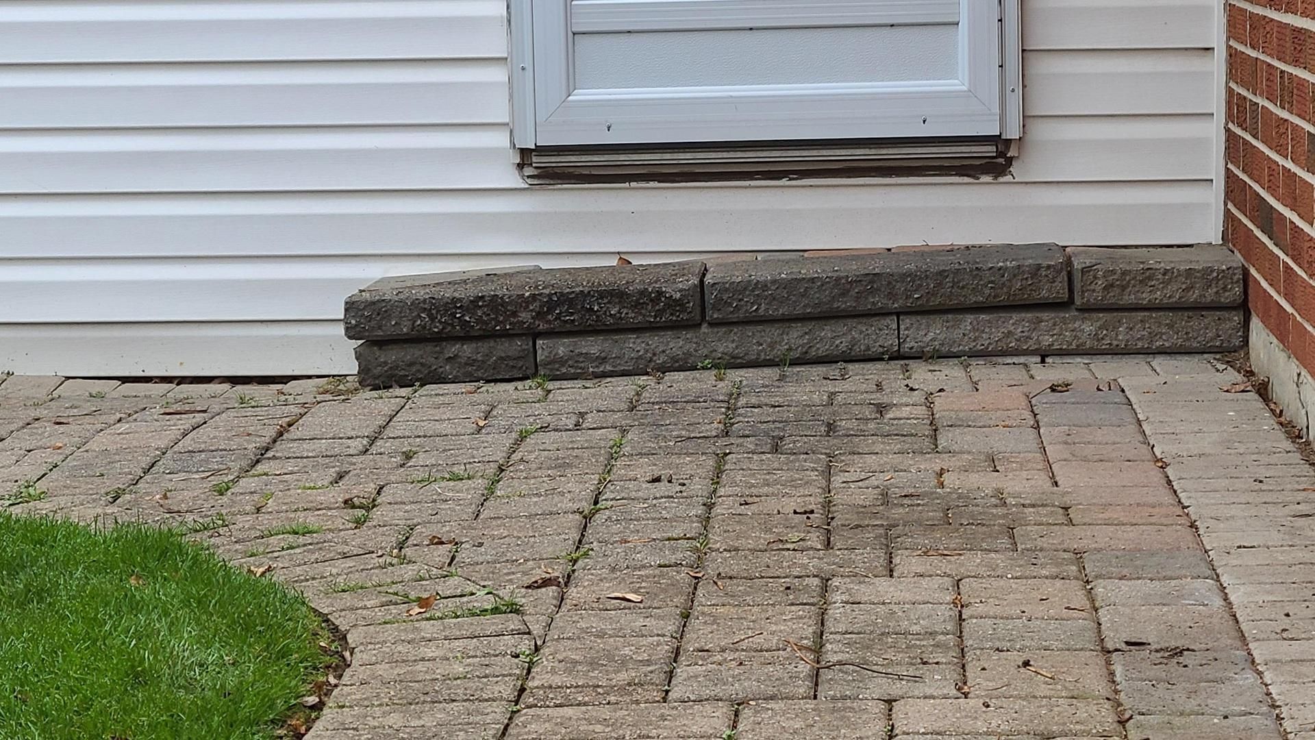 Uneven patio with shifted pavers and low spots, showing sinking caused by poor base preparation.