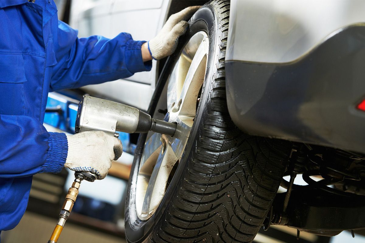 a man in a blue jacket is changing a tire on a car