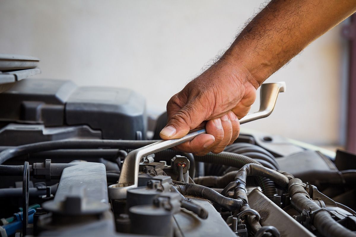 a man is working on a car engine with a wrench .