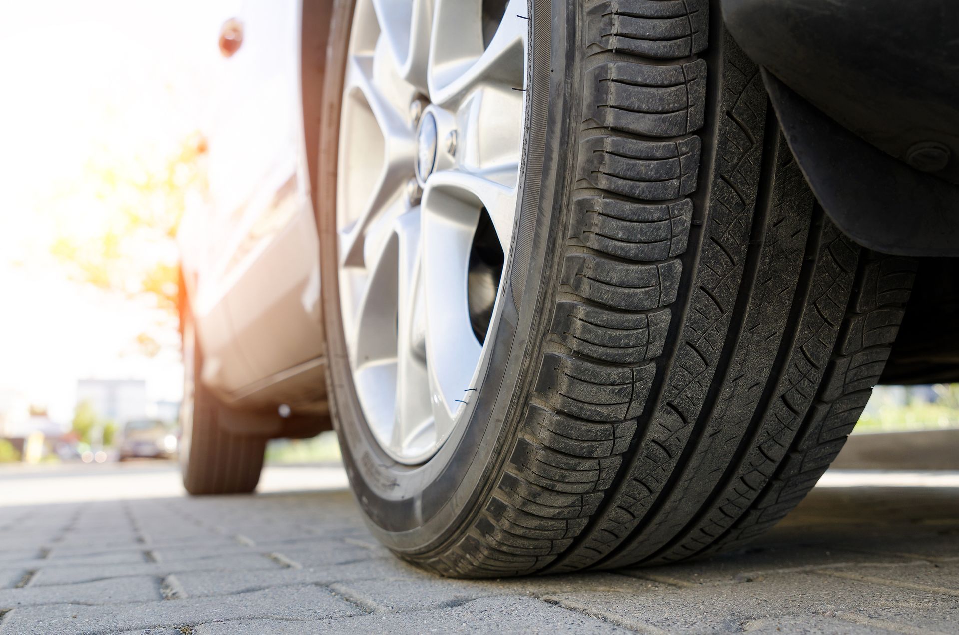 A close up of a car tire on a brick sidewalk.