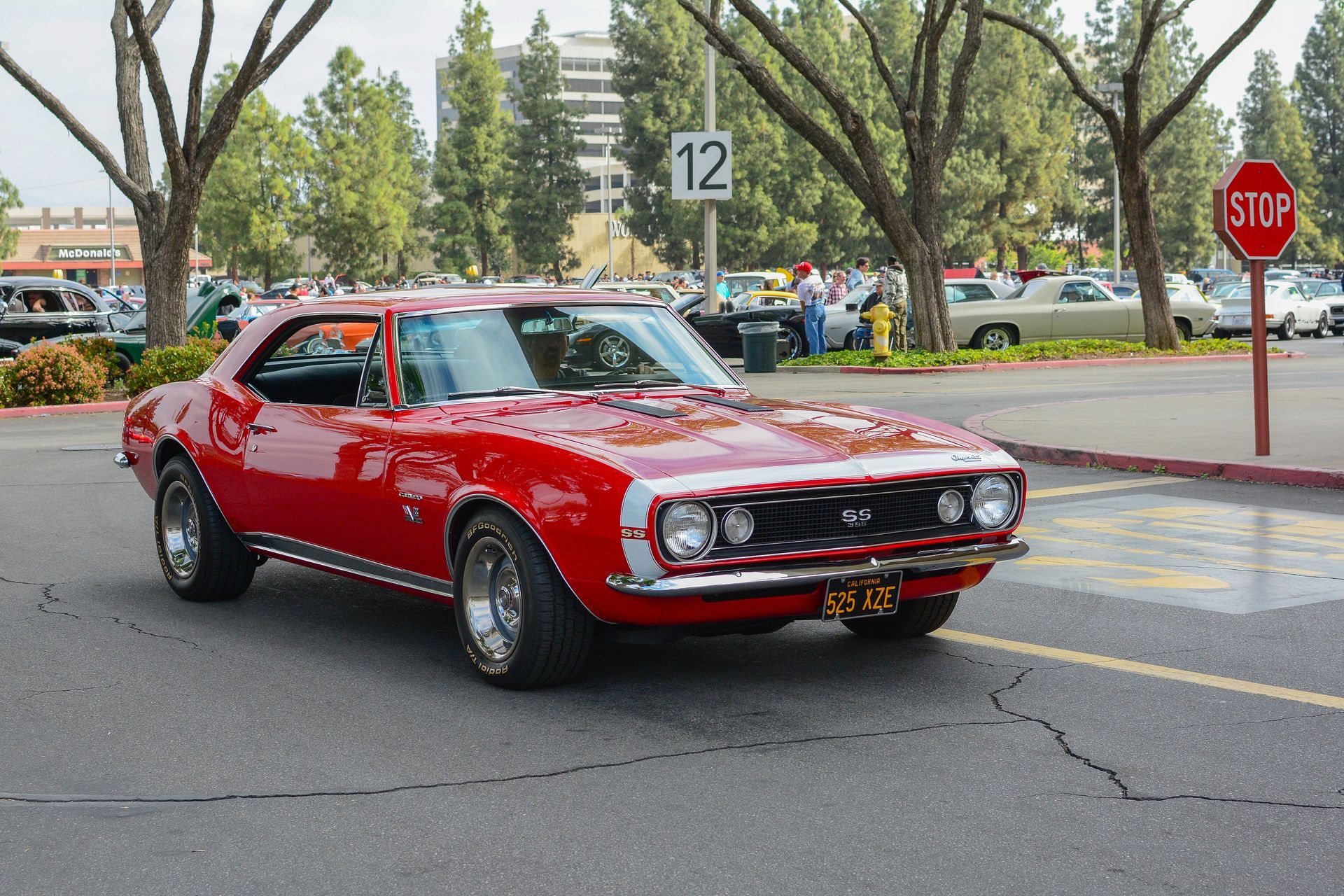 A red car is parked in front of a stop sign