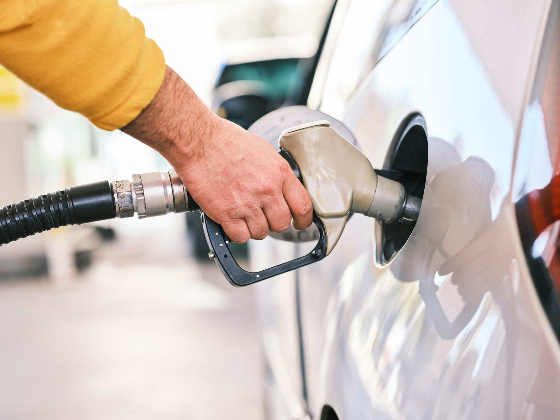 A man is pumping gas into a car at a gas station.