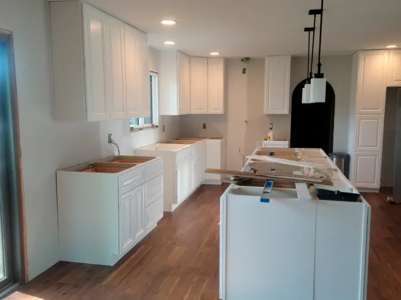 A kitchen with white cabinets and wooden floors is being remodeled.