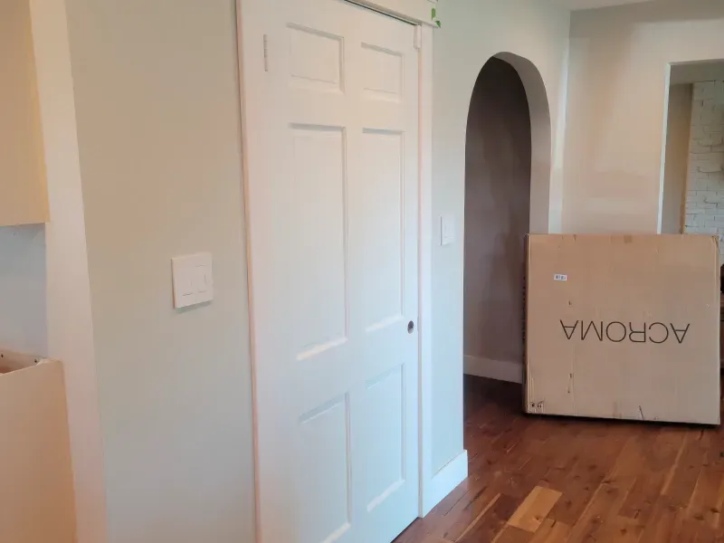 An empty room with a wooden floor and a white door.