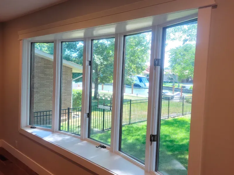 A large window in a room with a view of a fence and trees.