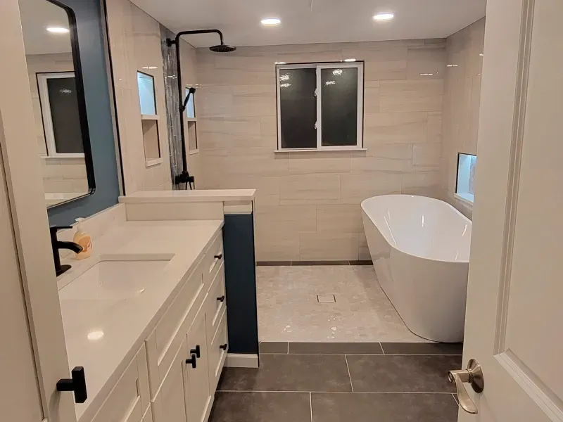 A bathroom with a tub , sink , mirror and shower.