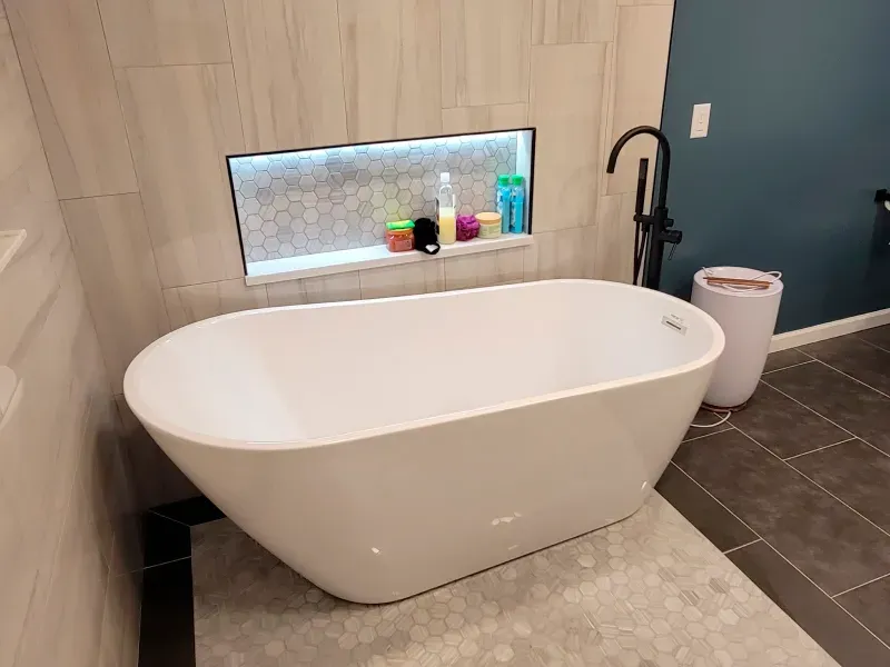 A white bathtub is sitting in a bathroom next to a toilet.